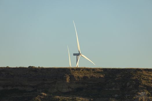 A newly installed wind turbine in the municipal area of the town of Gallur, appears with its huge blades behind the horizon of a distant hill, community of Aragon, Spain.