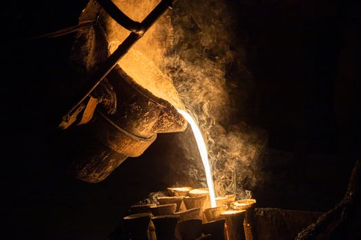 Industrial lost wax casting. The process of pouring for filling out ceramic shells with molten steel from ladle.