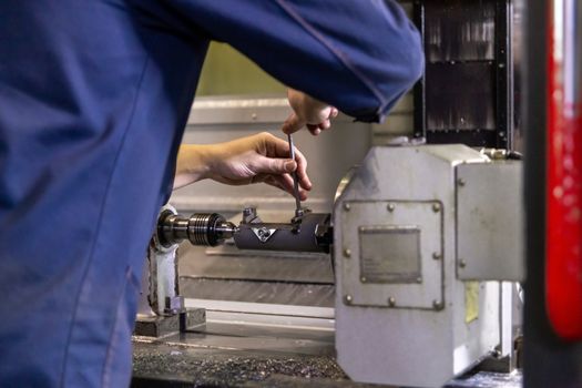 operator twisting bolts on fixture clamps inside of cnc milling machine with selective focus and foreground blur
