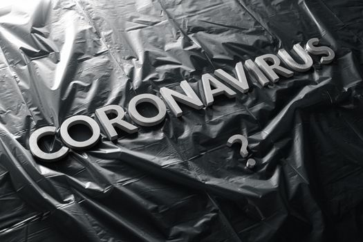 a question coronavirus laid with silver letters on black crumpled blue plastic film - diagonal composition with selective focus and dramatic light