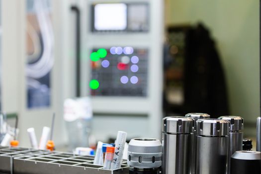 A set of shiny collet chucks in metalworking shop with blurry operational cnc milling machine inn the background.