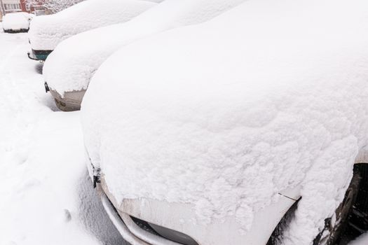 snow covered cars ofter blizzard at daylight parking - wide angle picture.