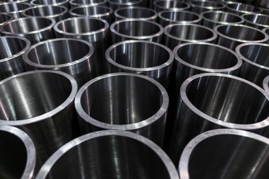 dark industrial background with cnc machined shiny steel pipes - selective focus and lens blur technique