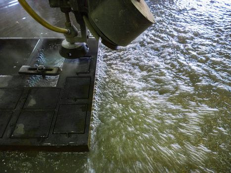 waterjet cutting process of thick black metal sheet.