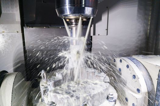 a process of industrial wet milling in 5-axis cnc machine with coolant flow under pressure and motion blur of streams and splashes.