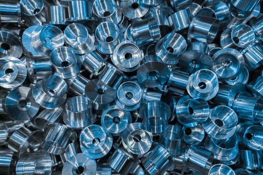 An industrial background with a pile of shiny metal cnc aerospace parts. Close-up full frame flat lay tech backdrop.