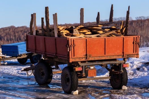 old rustic trailer with firewood lumber leftovers at winter daylight with selective focus