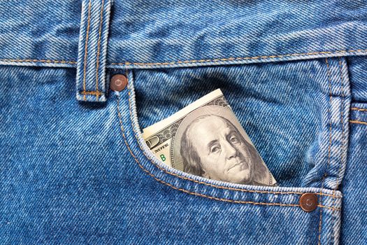 US dollar banknotes in the right front pocket of blue jeans. Concept of saving money or pocket expenses.