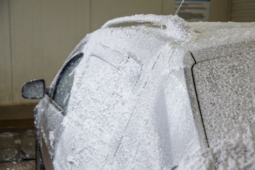 a car foam application process while washing indoors.