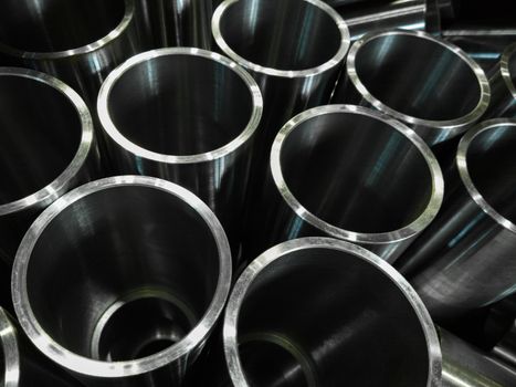 dark industrial background with cnc machined shiny steel pipes - selective focus and lens blur technique