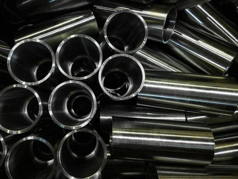 dark industrial background with cnc machined shiny steel pipes - selective focus and lens blur technique