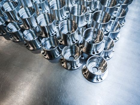 Shiny metal parts after cnc turning, drilling and machining on steel surface with selective focus for industrial background.