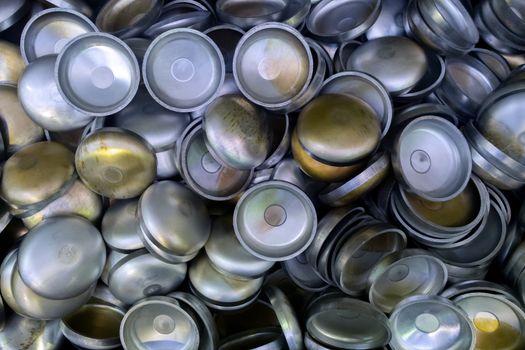 A batch of thick annealed alluminium stamped half-spherical parts. Random piled-up pattern with top-down view.