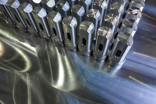 Batch of shiny metal parts after cnc turning and milling on flat milled surface with selective focus