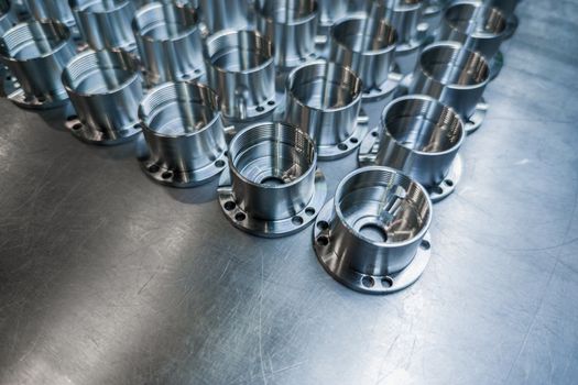Shiny metal parts after cnc turning, drilling and machining on steel surface with selective focus composition background.