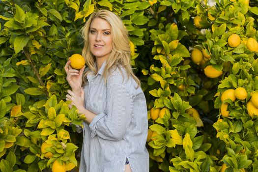 Blonde model posing outdoors with fruit from a lemon tree