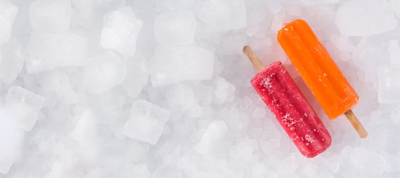Orange and strawberry popsicles on ice background