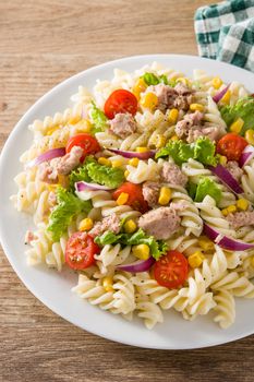 Pasta salad with vegetables in plate on wooden table