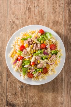 Pasta salad with vegetables in plate on wooden table