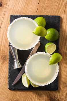 Margarita cocktails with lime in glass on wooden table.