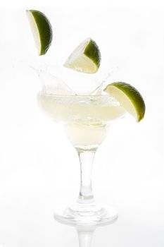 Margarita cocktail splash with limes falling inside isolated on white background