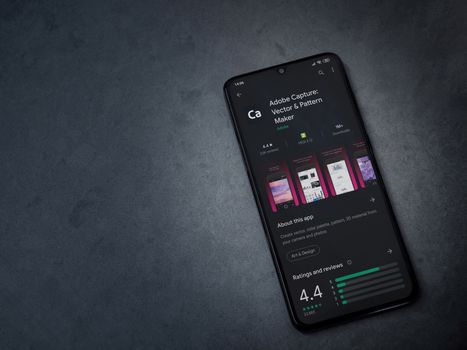 Lod, Israel - July 8, 2020: Adobe Capture - Vector and Pattern Maker app play store page on the display of a black mobile smartphone on a dark marble stone background. Top view flat lay with copy space.