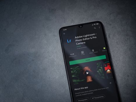 Lod, Israel - July 8, 2020: Adobe Lightroom - Photo Editor and Pro Camera app play store page on the display of a black mobile smartphone on a dark marble stone background. Top view flat lay with copy space.