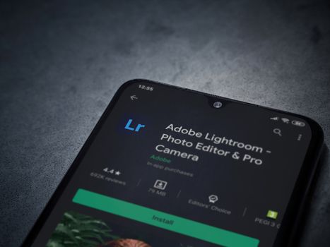 Lod, Israel - July 8, 2020: Adobe Lightroom - Photo Editor and Pro Camera app play store page on the display of a black mobile smartphone on a dark marble stone background. Top view flat lay with copy space.