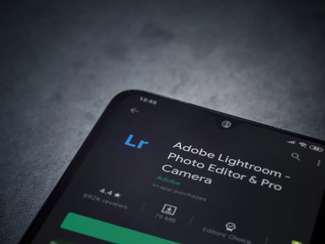 Lod, Israel - July 8, 2020: Adobe Lightroom - Photo Editor and Pro Camera app play store page on the display of a black mobile smartphone on a dark marble stone background. Top view flat lay with copy space.