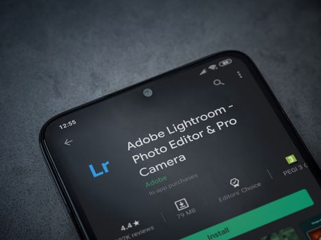 Lod, Israel - July 8, 2020: Adobe Lightroom - Photo Editor and Pro Camera app play store page on the display of a black mobile smartphone on a dark marble stone background. Top view flat lay with copy space.