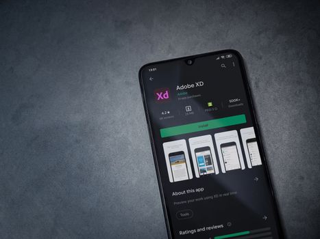 Lod, Israel - July 8, 2020: Adobe XD app play store page on the display of a black mobile smartphone on a dark marble stone background. Top view flat lay with copy space. 