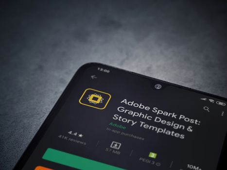 Lod, Israel - July 8, 2020: Adobe Spark Post - Graphic Design and Story Templates app play store page on the display of a black mobile smartphone on a dark marble stone background.Top view flat lay with copy space