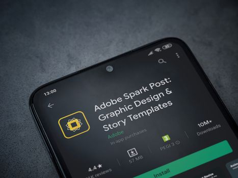 Lod, Israel - July 8, 2020: Adobe Spark Post - Graphic Design and Story Templates app play store page on the display of a black mobile smartphone on a dark marble stone background.Top view flat lay with copy space