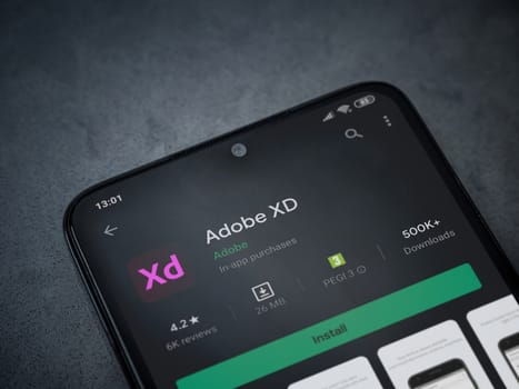 Lod, Israel - July 8, 2020: Adobe XD app play store page on the display of a black mobile smartphone on a dark marble stone background. Top view flat lay with copy space. 