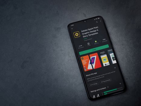 Lod, Israel - July 8, 2020: Adobe Spark Post - Graphic Design and Story Templates app play store page on the display of a black mobile smartphone on a dark marble stone background.Top view flat lay with copy space
