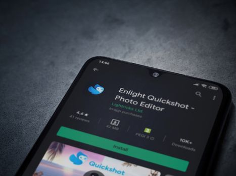 Lod, Israel - July 8, 2020: Enlight Quickshot app play store page on the display of a black mobile smartphone on a dark marble stone background. Top view flat lay with copy space.