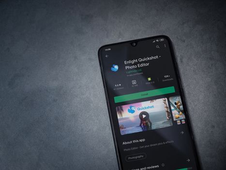 Lod, Israel - July 8, 2020: Enlight Quickshot app play store page on the display of a black mobile smartphone on a dark marble stone background. Top view flat lay with copy space.