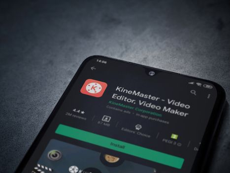 Lod, Israel - July 8, 2020: KineMaster - Video Editor and Movie Maker app play store page on the display of a black mobile smartphone on a dark marble stone background. Top view flat lay with copy space.