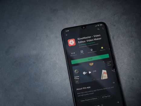 Lod, Israel - July 8, 2020: KineMaster - Video Editor and Movie Maker app play store page on the display of a black mobile smartphone on a dark marble stone background. Top view flat lay with copy space.