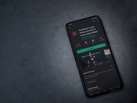 Lod, Israel - July 8, 2020: PixaMotion app play store page on the display of a black mobile smartphone on a dark marble stone background. Top view flat lay with copy space.