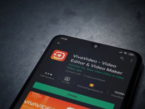 Lod, Israel - July 8, 2020: VivaVideo - Video Editor and Movie Maker app play store page on the display of a black mobile smartphone on a dark marble stone background. Top view flat lay with copy space.