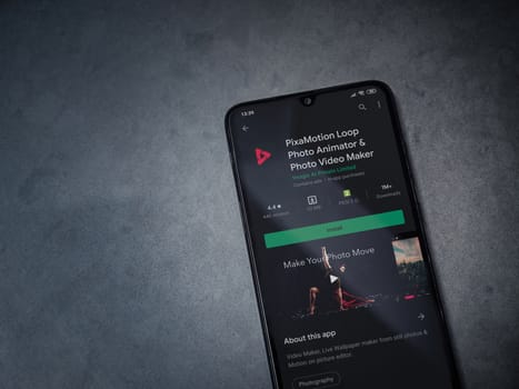 Lod, Israel - July 8, 2020: PixaMotion app play store page on the display of a black mobile smartphone on a dark marble stone background. Top view flat lay with copy space.