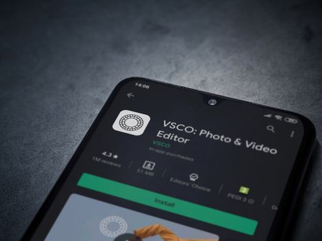 Lod, Israel - July 8, 2020: VSCO - Photo and Video Editor app play store page on the display of a black mobile smartphone on a dark marble stone background. Top view flat lay with copy space. 