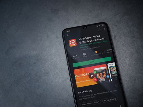 Lod, Israel - July 8, 2020: VivaVideo - Video Editor and Movie Maker app play store page on the display of a black mobile smartphone on a dark marble stone background. Top view flat lay with copy space.