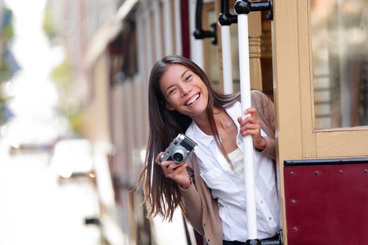 Travel lifestyle Asian woman tourist riding the famous tramway cable car system in San Francisco city, California during summer vacation. People having fun taking pictures with vintage camera.