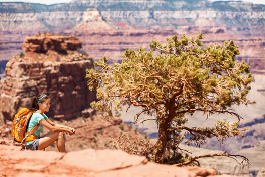 Girl hiker hiking on landscape trail in Grand Canyon National Park, USA. Adventure backpacker with bag sitting enjoying view of nature.