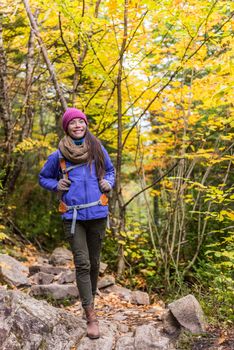 Hiking hiker girl with backpack walking on forest trail in mountains. Asian woman on autumn nature hike with backpack hat and jacket on fall adventure travel outdoors enjoying good weather.