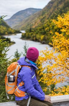 Woman hiker hiking looking at scenic view of fall foliage mountain landscape . Adventure travel outdoors person standing relaxing near river during nature hike in autumn season.