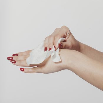 Young woman clean hands with wet wipes. Red nails