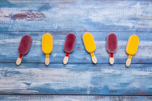 Fruit ice cream stick looking fresh to eat placed on a blue vintage wooden background.